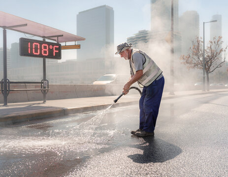 Worker cooling hot pavement during a heatwave