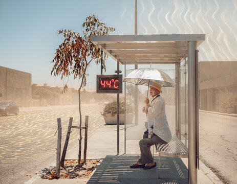 Person seeking shelter from extreme heat at a bus stop