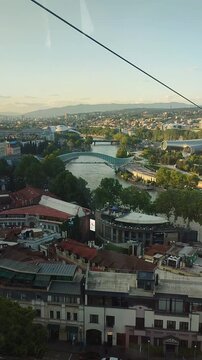 Aerial view of Tbilisi old town with cable car cabin, Rike park and Kura river at sunset.