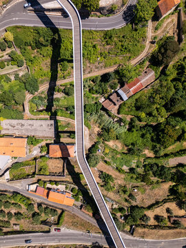 Aerial view of Carpinteira Pedestrian Bridge spanning over lush greenery and historic terracotta rooftops in the city of Covilha, Castelo Branco District, Portugal.