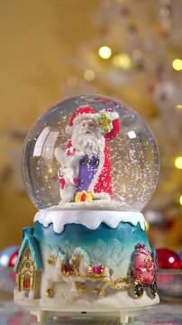 Santa claus snow globe with falling snow vertical video footage christmas decoration with bokeh lights and tree background festive holiday. 