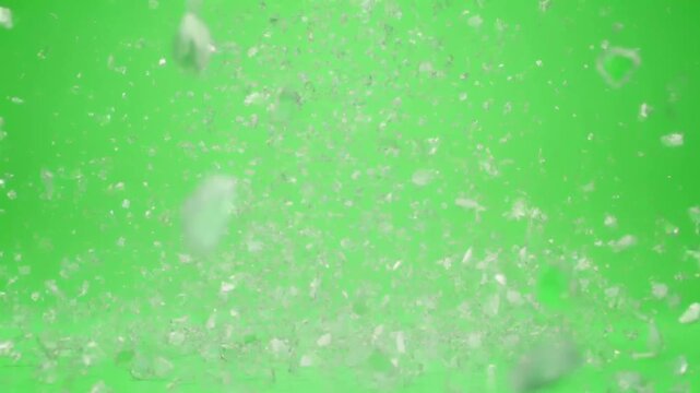 Small shattered ice particles flying on green screen background shot of numerous