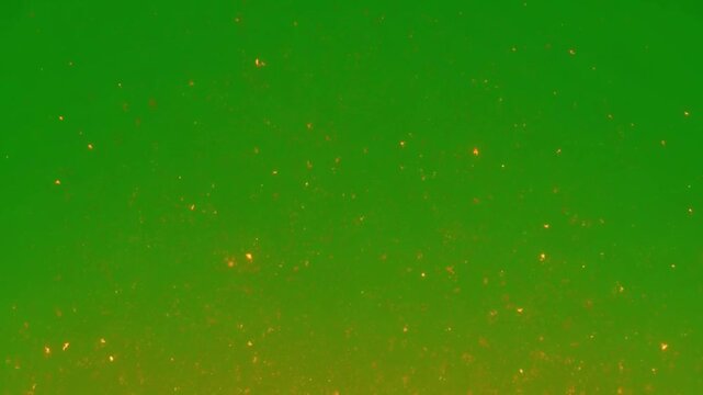 Warm glowing golden embers floating on green screen background a stream