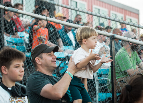 A father and his two sons sitting in the stadium stands, cheering and supporting their favorite team. A happy family enjoying a sports event together, showing excitement, teamwork, and the spirit 