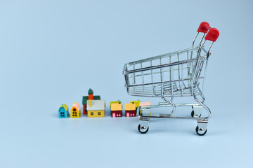 Mini shopping cart with red handles stands on blue surface © Nazir