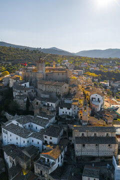 Aerial view of Castello Piccolomini in the historic hilltop town of Capestrano, featuring stone architecture, tiled rooftops, and surrounding hills in Capestrano, Abruzzo, Italy.