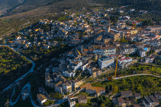 Aerial view of the historic town featuring a dense cluster of stone buildings, terracotta rooftops, and narrow streets nestled in the hills of Capestrano, Abruzzo, Italy.