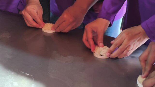 Close up shot of group of people hands making Rengginang, traditional Indonesian sticky rice crackers