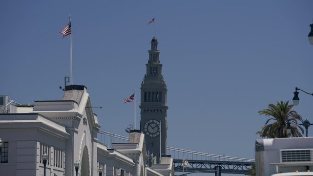 Old Ferry Building Clock Tower In San Francisco With American Flags - Low Shot