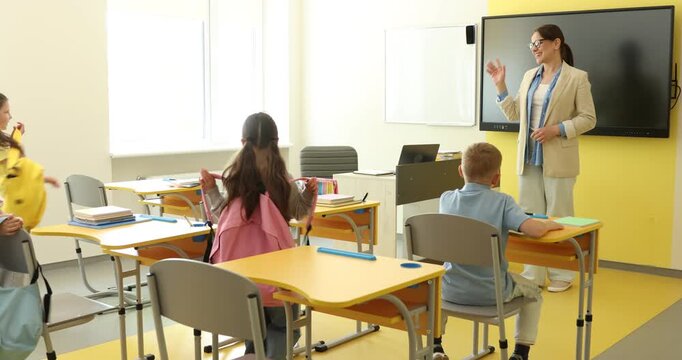 Teacher greeting students before lesson in classroom