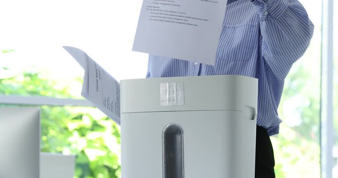 Woman destroying documents with shredder in office, closeup