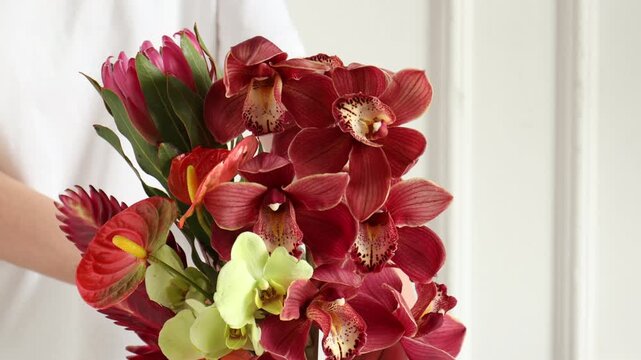 Woman with bouquet of tropical flowers indoors, closeup