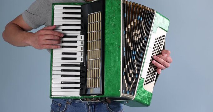 Man playing piano accordion on light background, closeup