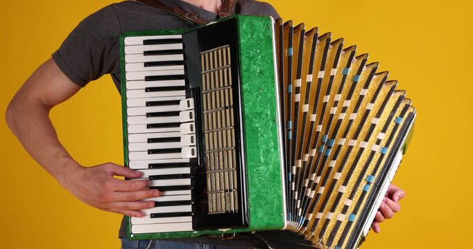 Man playing piano accordion on yellow background, closeup