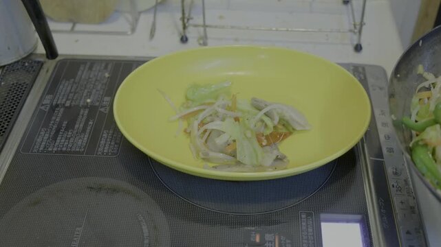 黄色い皿に鉄フライパンから肉野菜炒めを盛り付けるシーン　31秒