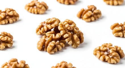 Fototapeta premium Close-up view of numerous shelled walnuts scattered on a clean white background, some lightly salted and ready for consumption.