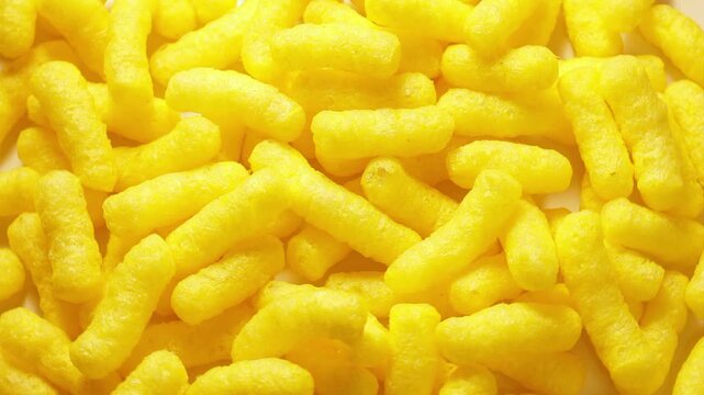 Close up of yellow corn sticks on a rotating table. Corn based processed foods