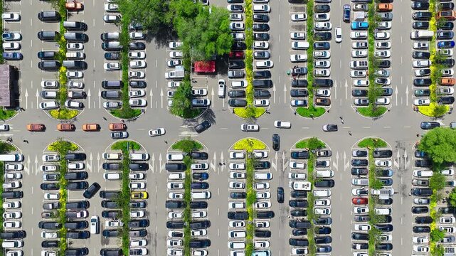Aerial top-down view of a crowded outdoor parking lot packed with organized rows of colorful cars.
