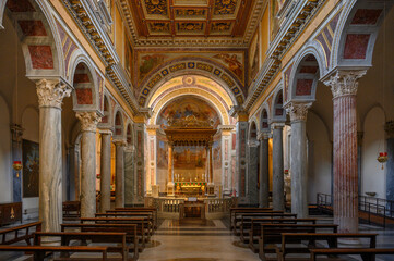 Interior view of the Basilica of San Nicola in Carcere in Rome, showing the nave with ancient columns recycled from pagan temples, a gilded coffered ceiling, and the high altar ciborium © Franco Tognarini