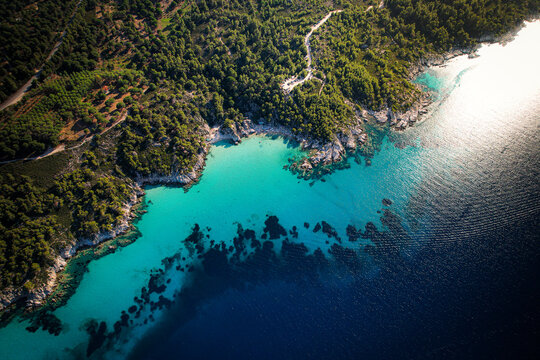 Aerial view of Sithonia peninsula with turquoise waters, rocky coastline, and dense pine forests in Halkidiki, Greece.