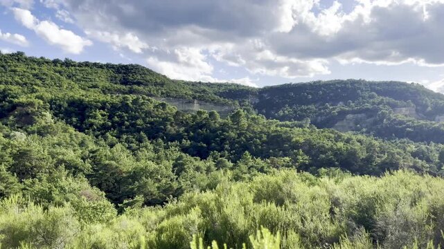 Panning view over forested Luberon hills with pale limestone