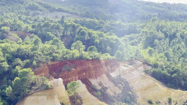 Panorama over eroded red and white ochre cliffs surrounded by dense