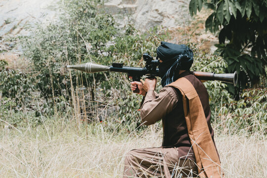 Outdoor military concept. Armed man, kneeling soldier in grass with rocket launcher in outdoor field
