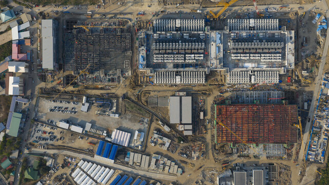 Khlong Tamru, Chon Buri, Thailand - 09 March 2026: Aerial view of Bridge Data Center construction site showing large industrial buildings, heavy machinery, cranes, and parking areas.