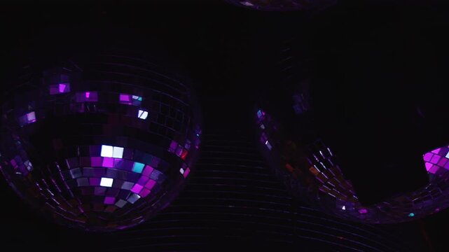 Vibrant celebration unfolds as shimmering disco balls cast dazzling red and green reflections across dark space, setting perfect mood for birthday bash at pulsating club during exciting night.