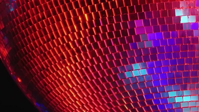 Experience the dazzling glow of a mirror ball at a lively disco party. Brilliant green, red, and blue lights swirl across the reflective surface during a joyous birthday celebration.