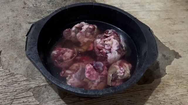 Washing fresh raw goat meat in black basin close up