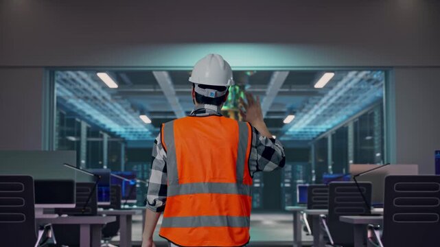 Back of Asian Male Engineer Waving Hand Saying Bye While Walking at Futuristic Quantum Computer Data Center Control Room