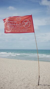 4K 60P Red warning flag blowing in the wind on beach prohibiting swimming