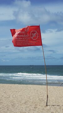 4K Slow motion red warning flag blowing in the wind on beach