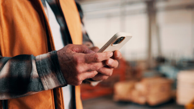 Carpentry, hands and phone with man in warehouse for feedback, management or planning. App, communication and space with person in woodworking factory for furniture manufacturing or production