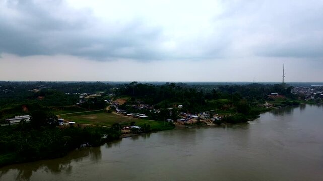Aerial View of Wide Tropical River in Ecuador with Forested Banks, Cloudy Sky, Rural Settlement and Remote Amazon Waterway Landscape