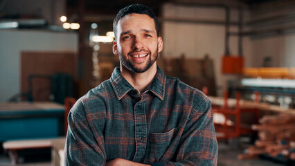 Obraz premium Carpentry, portrait and man in warehouse with arms crossed, handyman or pride in manufacturing industry. Smile, ambition or artisan with about us, production career or confidence in woodworking.