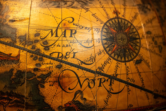 Detailed close-up of an antique world globe highlighting a decorative compass rose and vintage cartographic artwork.