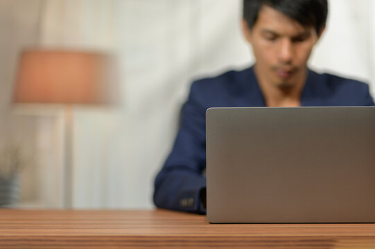 Professional man working on laptop at desk in modern indoor office environment