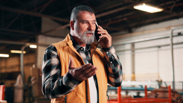 Carpentry, conflict and phone call with man in warehouse for management or problem solving. Feedback, manufacturing and production with mature person in woodworking factory for mobile disagreement