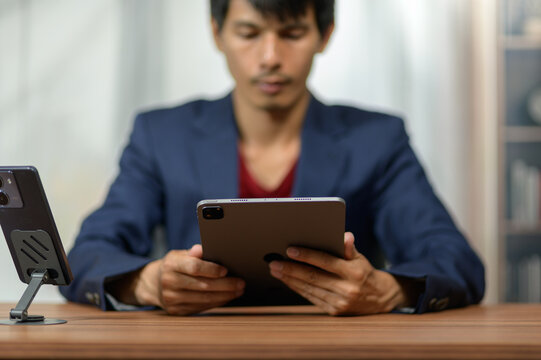 Young Asian Man Using Digital Tablet at Workspace in Modern Office Environment