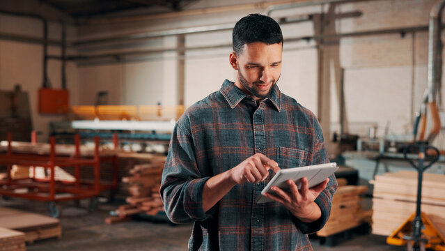 Man, tablet and scroll in woodworking workshop, check lumber order or online inventory management. Carpenter, smile and reading on tech for digital stock analysis or search carpentry merchandise app