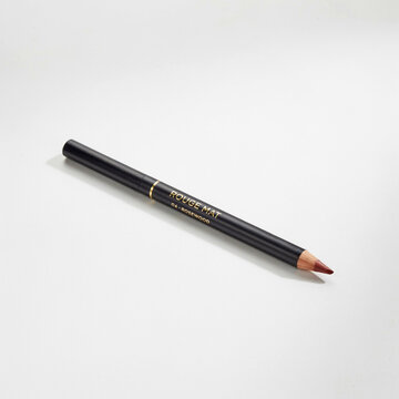 A stylish black cosmetic lip liner pencil displaying a perfectly sharpened rosewood colored tip and a sophisticated gold text label for precise lip makeup application essential for cosmetic use