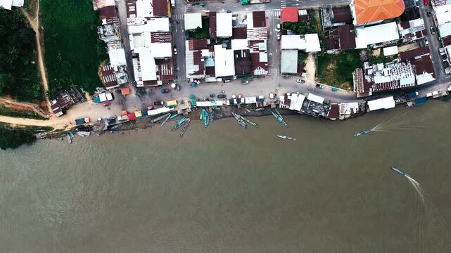 Top Down Drone View of Riverfront Market and Canoes in Ecuador Amazon Town, Brown Water, Boats, Buildings and Local Transport Scene