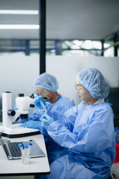 Scientists examining a laboratory sample using microscope and digital technology in a modern biomedical research lab, advancing healthcare, diagnostics and biotechnology.