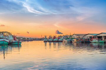 Naklejka premium Colorful Fishing Boats Docked at Harbor During Vibrant Sunset
