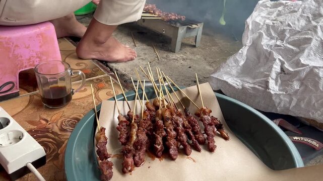 Freshly grilled chicken satay with street food cooking process background