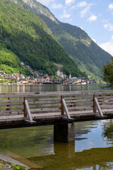 Fototapeta premium Wooden footbridge with traditional alpine village and mountains in the background