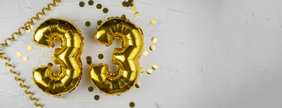 Yellow Gold foil balloon number thirty-three on a concrete background. Birthday card with lettering 33. Anniversary concept. For anniversary, birthday, wedding event, new year celebration.