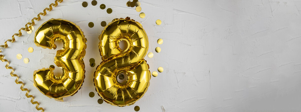 Yellow Gold foil balloon number thirty-eight on a concrete background. Birthday card with lettering 38. Anniversary concept. For anniversary, birthday, wedding event, new year celebration.